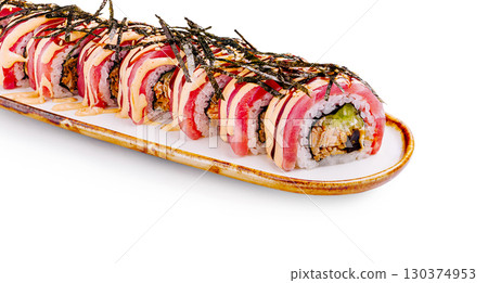 Sushi roll delicately arranged on a white plate with garnishes 130374953