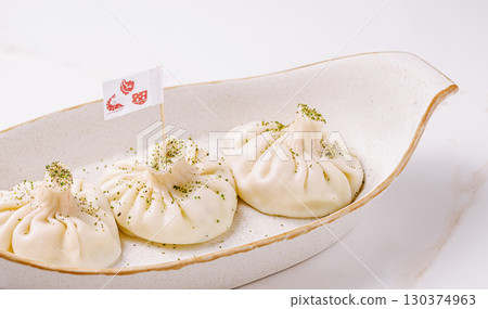 Dumplings served on a white plate with decorative flag and seasoning Dumplings served on a white plate with decorative flag and seasoning 130374963