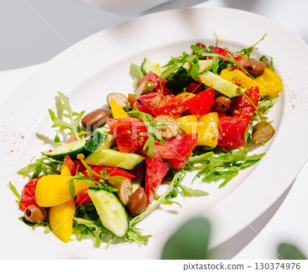 Fresh summer salad with colorful vegetables and olives on a white plate 130374976