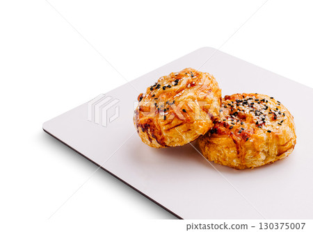 Delicious baked pastries topped with sesame seeds on a white platter 130375007