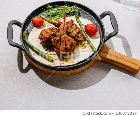 Delicious grilled meat served on a hot plate with vegetables Delicious grilled meat served on a hot plate with vegetables 130375017