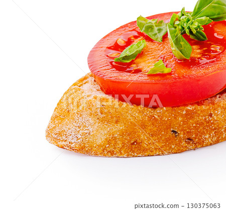Fresh tomato and basil atop crusty bread slice with vibrant colors Fresh tomato and basil atop crusty bread slice with vibrant colors 130375063