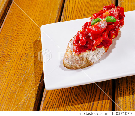 Delicious bruschetta with fresh tomatoes and basil on a white plate 130375079