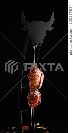 Juicy cut of meat hanging on a skewer in a modern dining setting 130375084