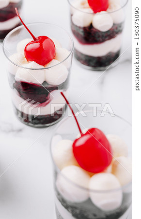 Layered dessert cups with cream and cherries create a sweet delight Layered dessert cups with cream and cherries create a sweet delight 130375090