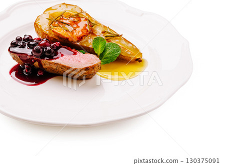 Gourmet duck breast with roasted pear and berry sauce on elegant plate 130375091