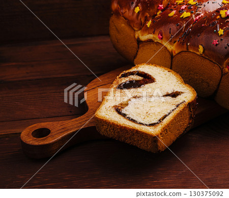 Freshly baked sweet bread with chocolate filling on wooden board Freshly baked sweet bread with chocolate filling on wooden board 130375092