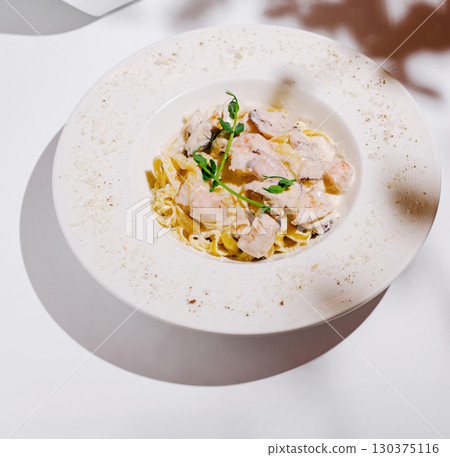 Delicious seafood pasta dish with creamy sauce and fresh herbs served on white table 130375116