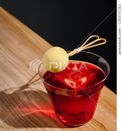 Colorful cocktail with garnish on wooden table in modern bar setting Colorful cocktail with garnish on wooden table in modern bar setting 130375162
