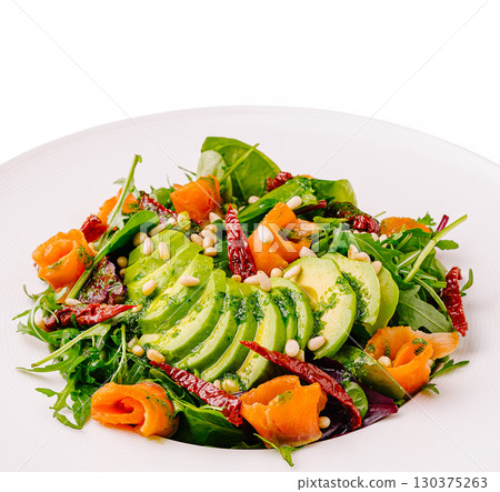 Fresh salad with avocado, smoked salmon, and herbs on a white plate 130375263
