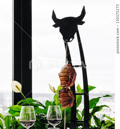 Culinary experience of hanging grilled meat with city views at sunset 130375273