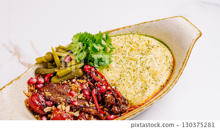 Colorful dish featuring meat, grains, and garnishes in a modern setting Colorful dish featuring meat, grains, and garnishes in a modern setting 130375281