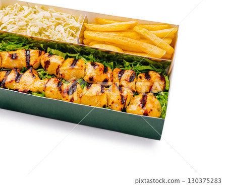 Grilled chicken skewers with coleslaw and golden fries served on a tray 130375283