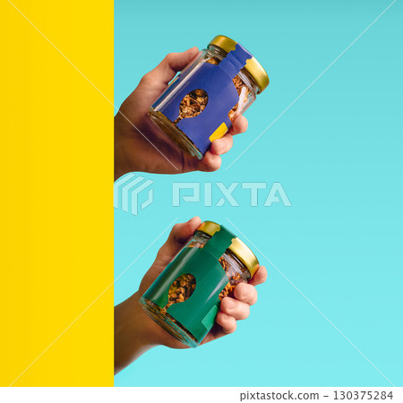 Hands hold colorful jars of granola against a bright background Hands hold colorful jars of granola against a bright background 130375284