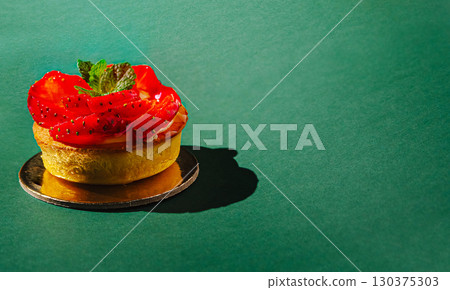 Fresh strawberry tartlet with mint on a green background Fresh strawberry tartlet with mint on a green background 130375303