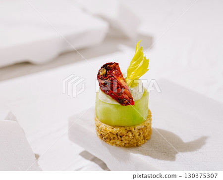 Delicate cucumber appetizer with sun-dried tomato and creamy topping 130375307