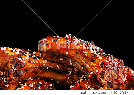 Tender barbecue ribs coated in sesame seeds on a dark background 130375323