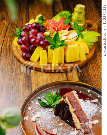 Delicious fruit platter and dessert showcase at a cozy dining setting 130375332