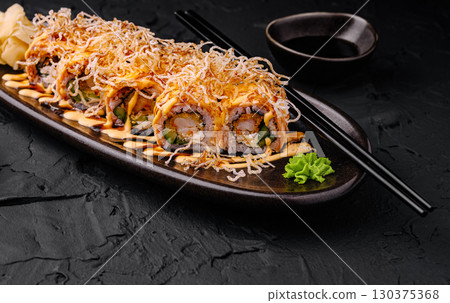 Colorful sushi rolls with garnishes served on a dark plate 130375368