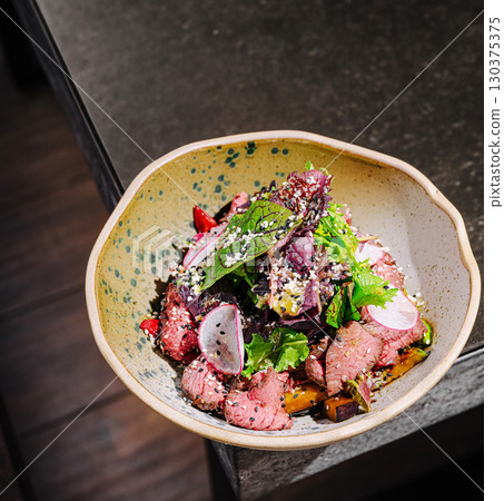 Colorful dish of roasted vegetables and fresh greens served in a bowl 130375375