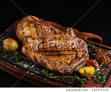 Delicious grilled steak served with roasted vegetables on wooden platter 130375379