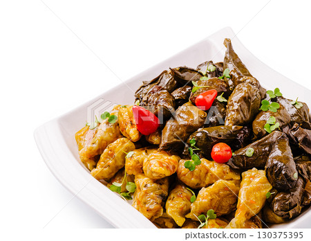 Yummy stuffed grape leaves and vegetables served on a white plate 130375395