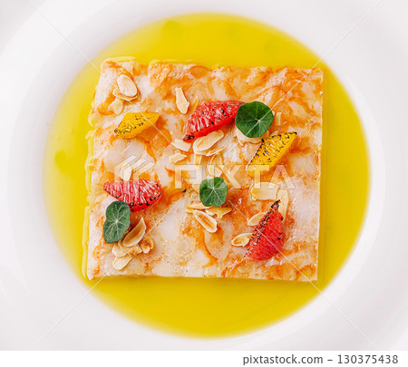 Delicious dessert presented on a white plate with bright garnishes and oil Delicious dessert presented on a white plate with bright garnishes and oil 130375438
