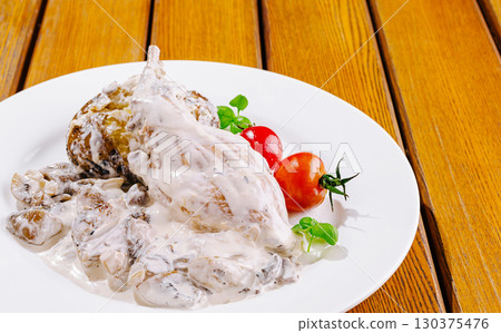 Creamy chicken dish served with fresh vegetables on a wooden table 130375476