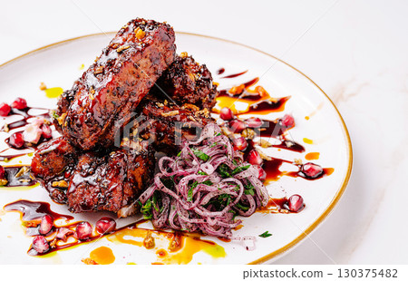 Delicious grilled meat with pomegranate and onion salad served beautifully Delicious grilled meat with pomegranate and onion salad served beautifully 130375482