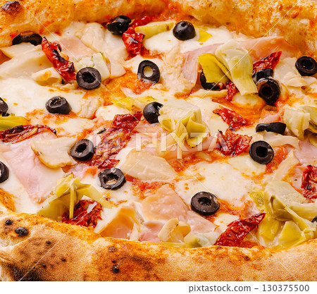 Gourmet pizza topped with artichokes, olives, and sun-dried tomatoes 130375500