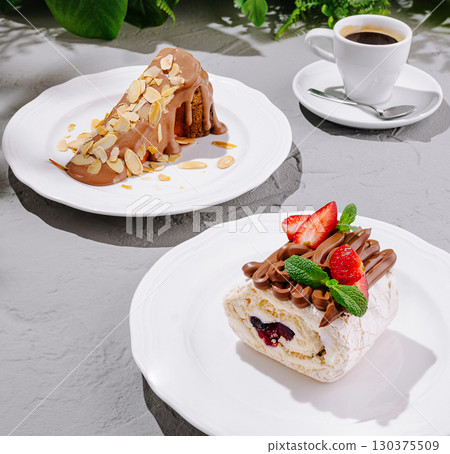 Desserts on white plates with coffee in a cozy cafe setting Desserts on white plates with coffee in a cozy cafe setting 130375509