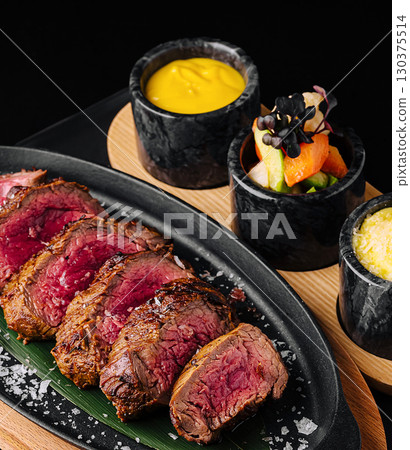 Tender grilled steak served with vibrant side dishes on a platter 130375514