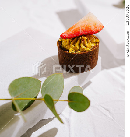 Delicious dessert featuring a strawberry on a rich pastry tart with cream 130375520