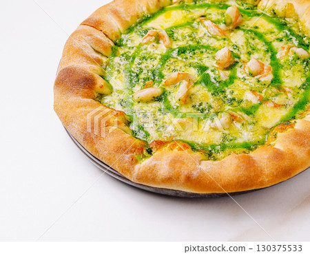 Unique green pesto pizza topped with shrimp served on white table 130375533