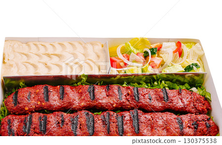 Delicious grilled kebabs served with fresh salad and creamy dip 130375538