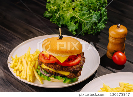 Gourmet burger with fresh ingredients and crispy fries on a wooden table 130375547