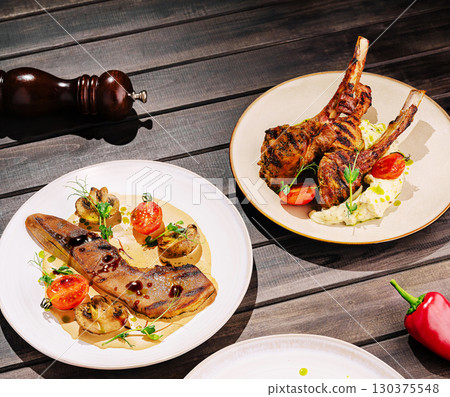 Delicious grilled lamb chops and flavorful fish dish served in a rustic setting 130375548