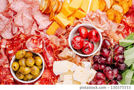 Culinary display of assorted meats, cheeses, and fresh produce at a gathering 130375553