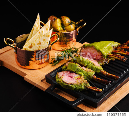 Deliciously prepared lamb rack with green herb crust and sides Deliciously prepared lamb rack with green herb crust and sides 130375565