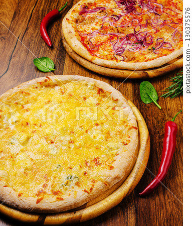 Two delicious pizzas served on wooden boards with fresh ingredients Two delicious pizzas served on wooden boards with fresh ingredients 130375576