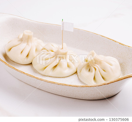 Steaming dumplings or khinkali served in a white dish at a restaurant 130375606