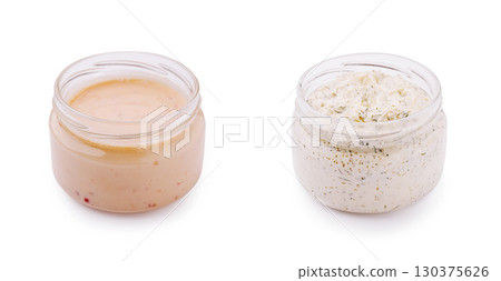 Different types of creamy sauces in glass jars on white background 130375626