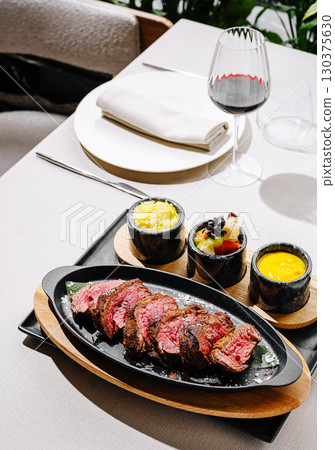 Savory steak with sides and wine in a stylish dining setting Savory steak with sides and wine in a stylish dining setting 130375630