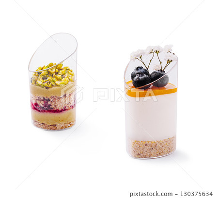 Delicious dessert cups with layers of cream and fruit on a white background 130375634
