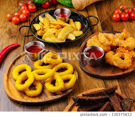 Delicious assortment of fried snacks served on wooden platters 130375652
