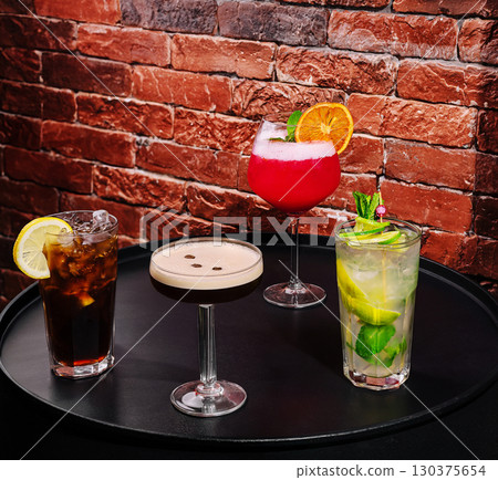 Vibrant assortment of cocktails served on a black table in a bar setting Vibrant assortment of cocktails served on a black table in a bar setting 130375654
