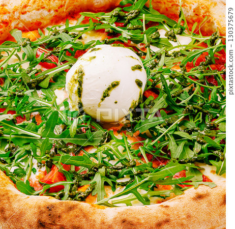 Freshly made pizza topped with arugula and creamy cheese at a rustic eatery 130375679
