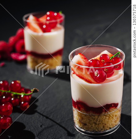 Delicious layered dessert with fresh fruit served in clear cups 130375718