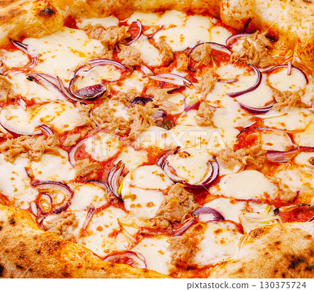 Flavorful pizza topped with cheese, red onions, and tuna in a warm kitchen Flavorful pizza topped with cheese, red onions, and tuna in a warm kitchen 130375724