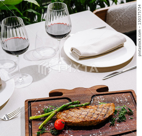 Tasty grilled steak with veggies and red wine in a restaurant Tasty grilled steak with veggies and red wine in a restaurant 130375734